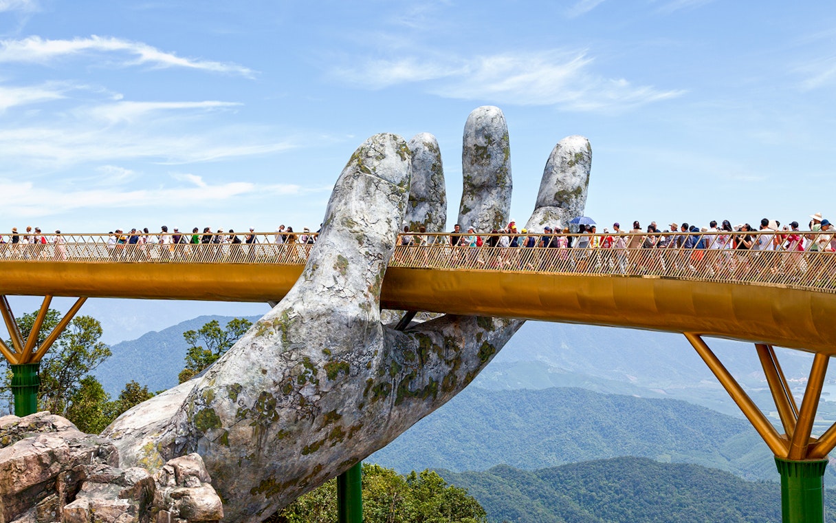 Golden Bridge held by giant hands at Ba Na Hills, Da Nang, with tourists walking.