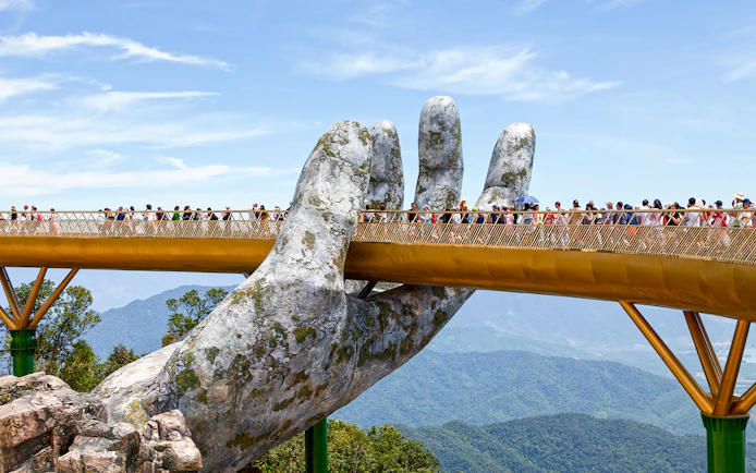 Golden Bridge held by giant hands at Ba Na Hills, Da Nang, with tourists walking.