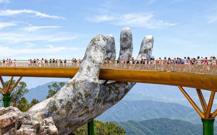 Golden Bridge held by giant hands at Ba Na Hills, Da Nang, with tourists walking.