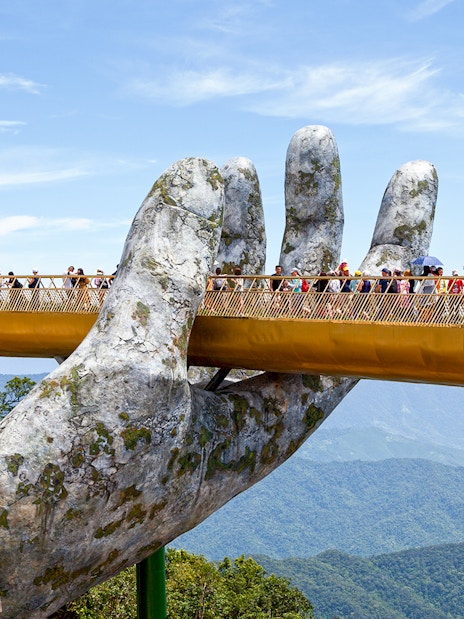 Golden Bridge held by giant hands at Ba Na Hills, Da Nang, with tourists walking.