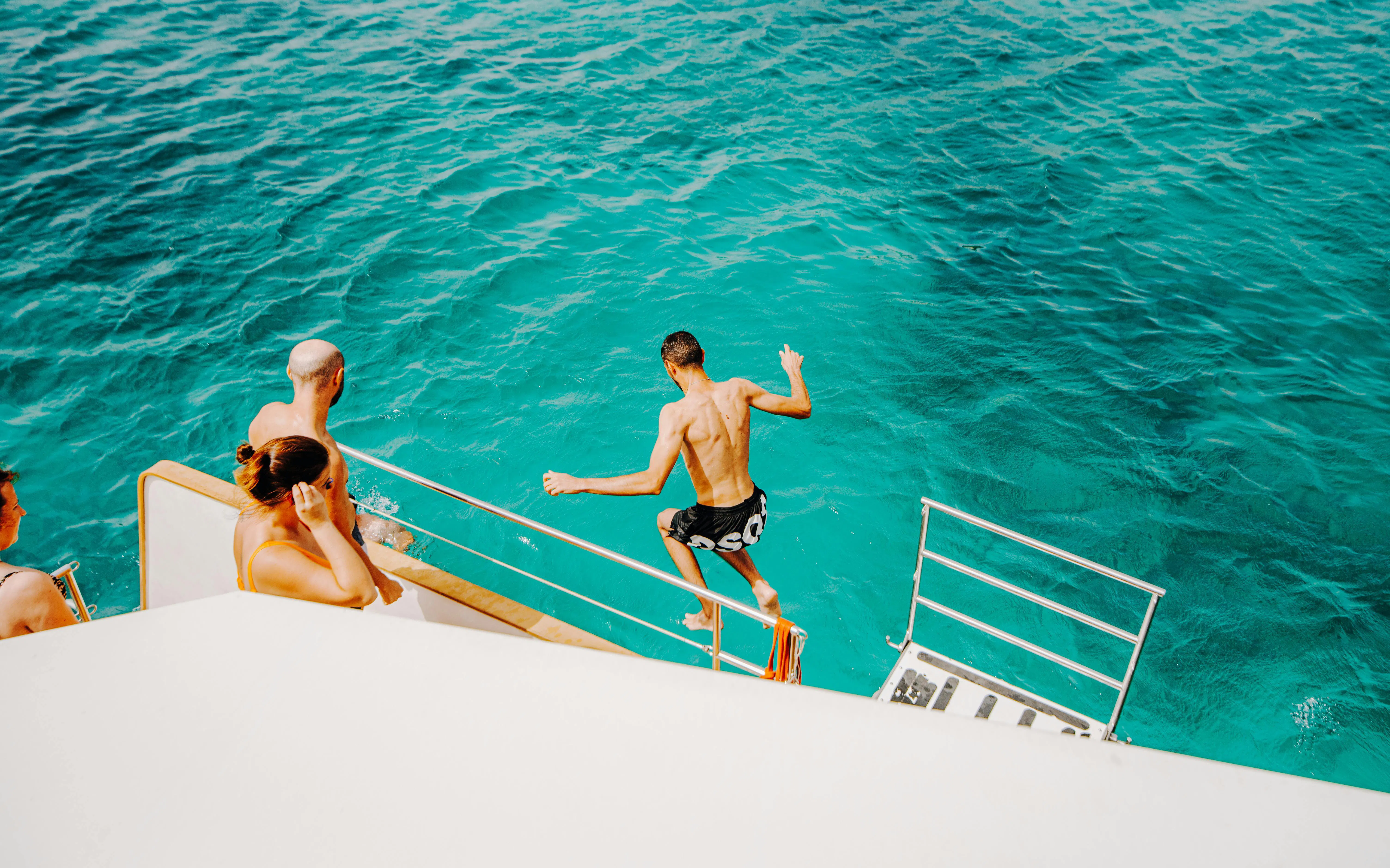 Person jumping off boat into turquoise water during La Graciosa Island cruise.