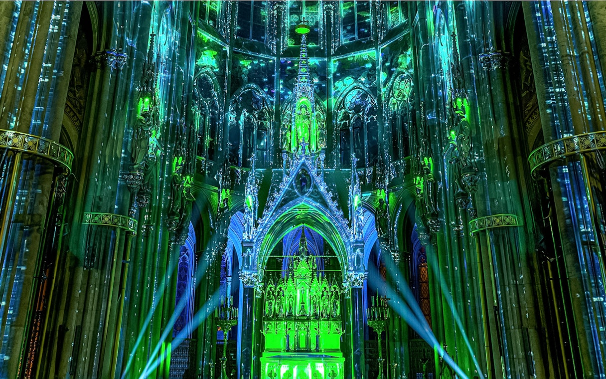Votivkirche interior illuminated with green and blue lights during Light of Creation event in Vienna.