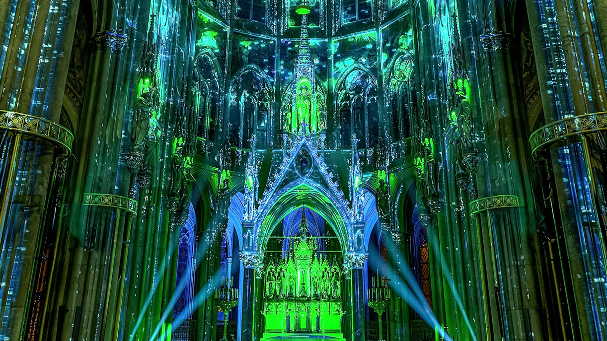Votivkirche interior illuminated with green and blue lights during Light of Creation event in Vienna.