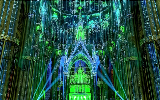 Votivkirche interior illuminated with green and blue lights during Light of Creation event in Vienna.