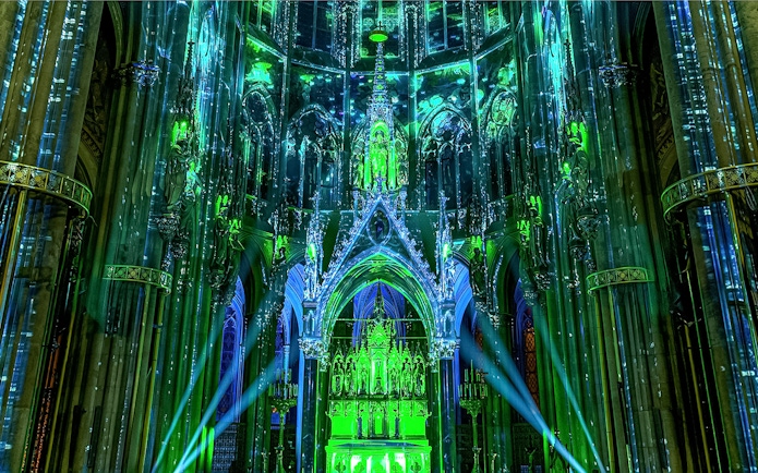 Votivkirche interior illuminated with green and blue lights during Light of Creation event in Vienna.