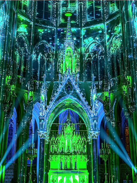 Votivkirche interior illuminated with green and blue lights during Light of Creation event in Vienna.