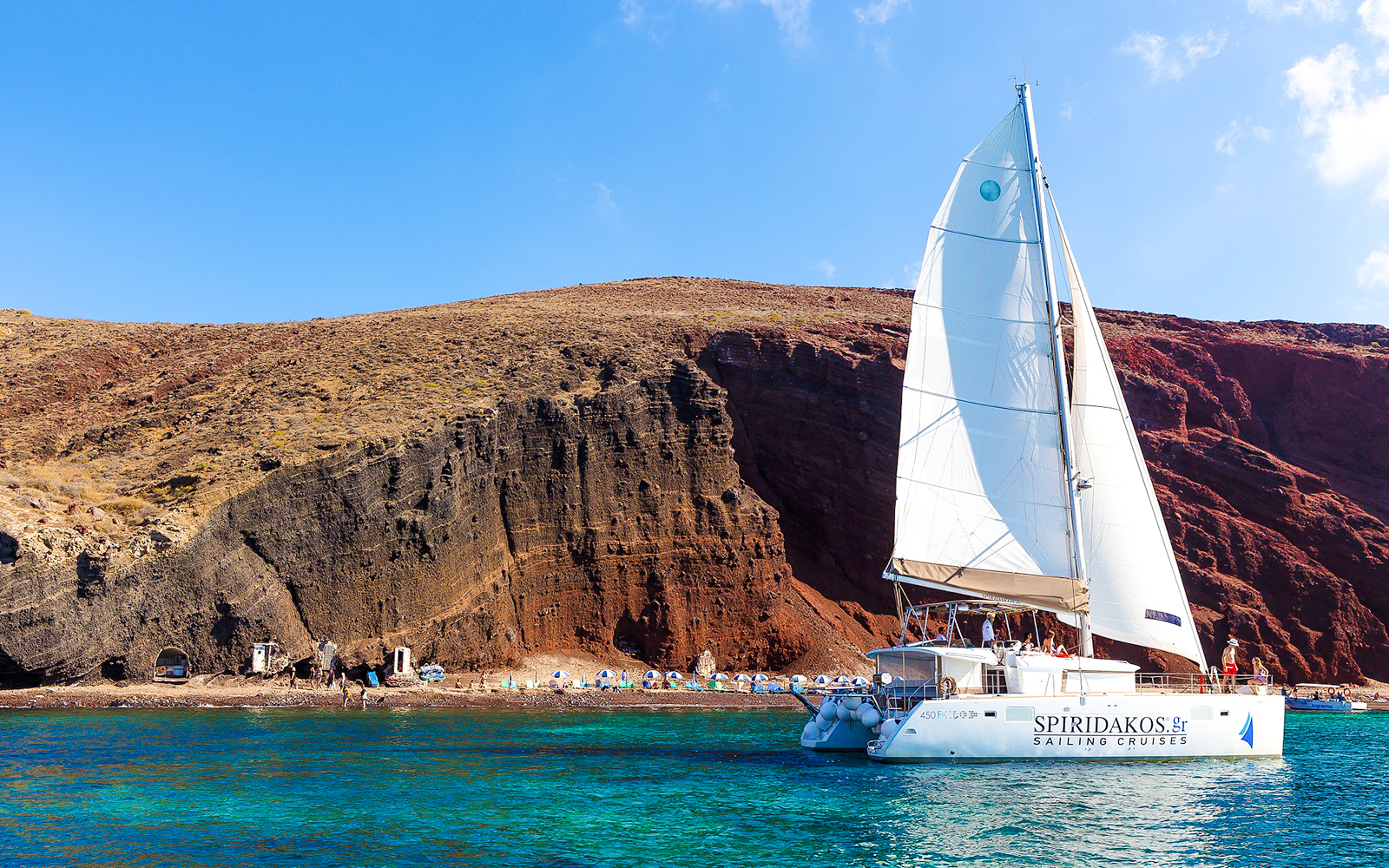 Catamaran sailing near the cliffs of Santorini on the Joy Daytime Cruise.