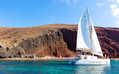 Catamaran sailing near the cliffs of Santorini on the Joy Daytime Cruise.