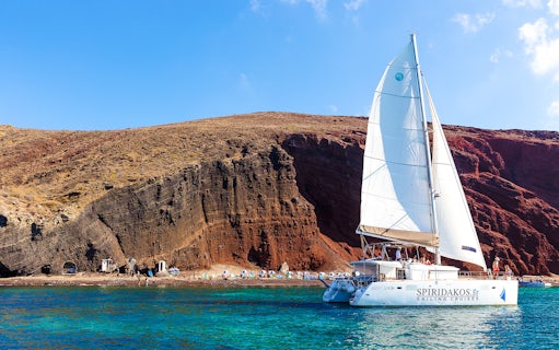 Catamaran sailing near the cliffs of Santorini on the Joy Daytime Cruise.