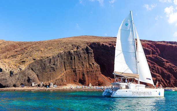 Catamaran sailing near the cliffs of Santorini on the Joy Daytime Cruise.