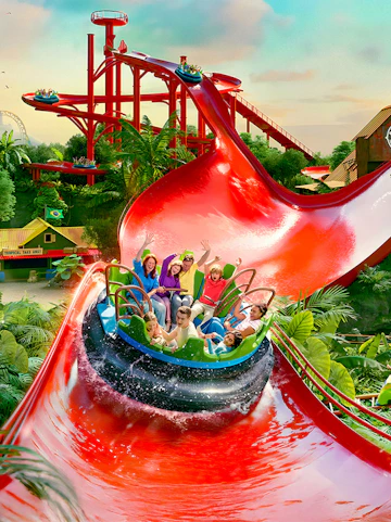 Visitors enjoying a water ride at Bellewaerde Park with vibrant red slides and lush greenery.