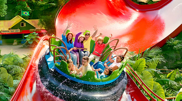 Visitors enjoying a water ride at Bellewaerde Park with vibrant red slides and lush greenery.