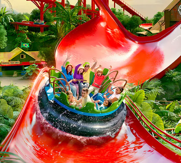 Visitors enjoying a water ride at Bellewaerde Park with vibrant red slides and lush greenery.
