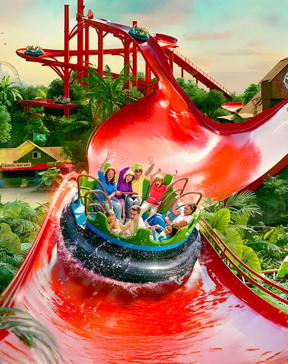 Visitors enjoying a water ride at Bellewaerde Park with vibrant red slides and lush greenery.