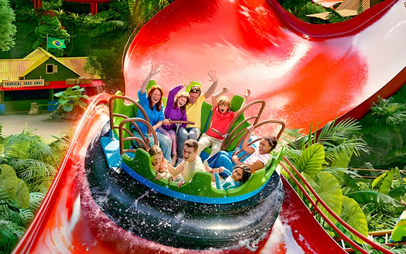 Visitors enjoying a water ride at Bellewaerde Park with vibrant red slides and lush greenery.