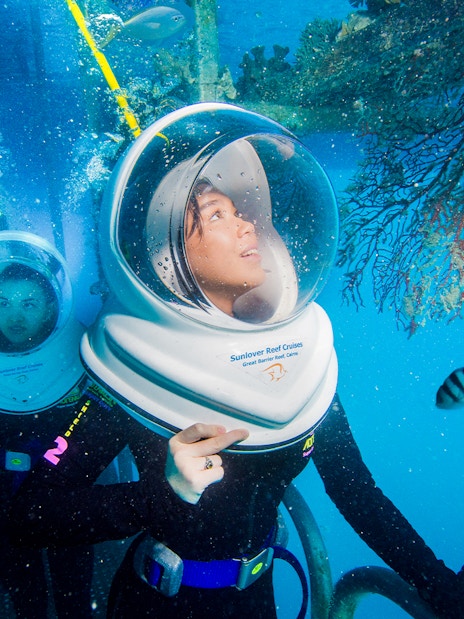 Tourists on Seawalker helmet dive at Moore Reef, Great Barrier Reef, observing coral and fish.