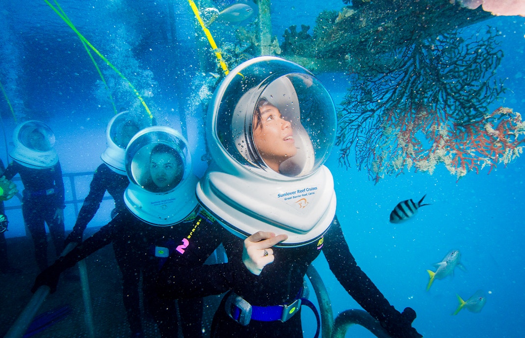 Tourists on Seawalker helmet dive at Moore Reef, Great Barrier Reef, observing coral and fish.