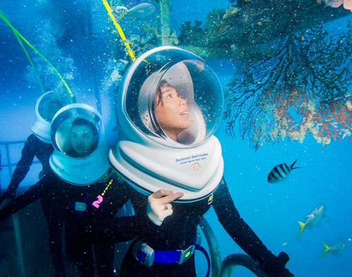 Tourists on Seawalker helmet dive at Moore Reef, Great Barrier Reef, observing coral and fish.