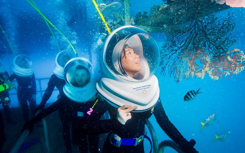 Tourists on Seawalker helmet dive at Moore Reef, Great Barrier Reef, observing coral and fish.