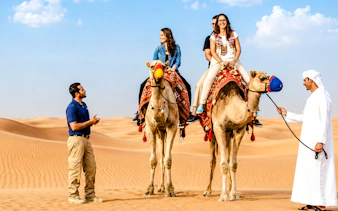 Camel ride in Abu Dhabi desert with guide and tourists on camels.