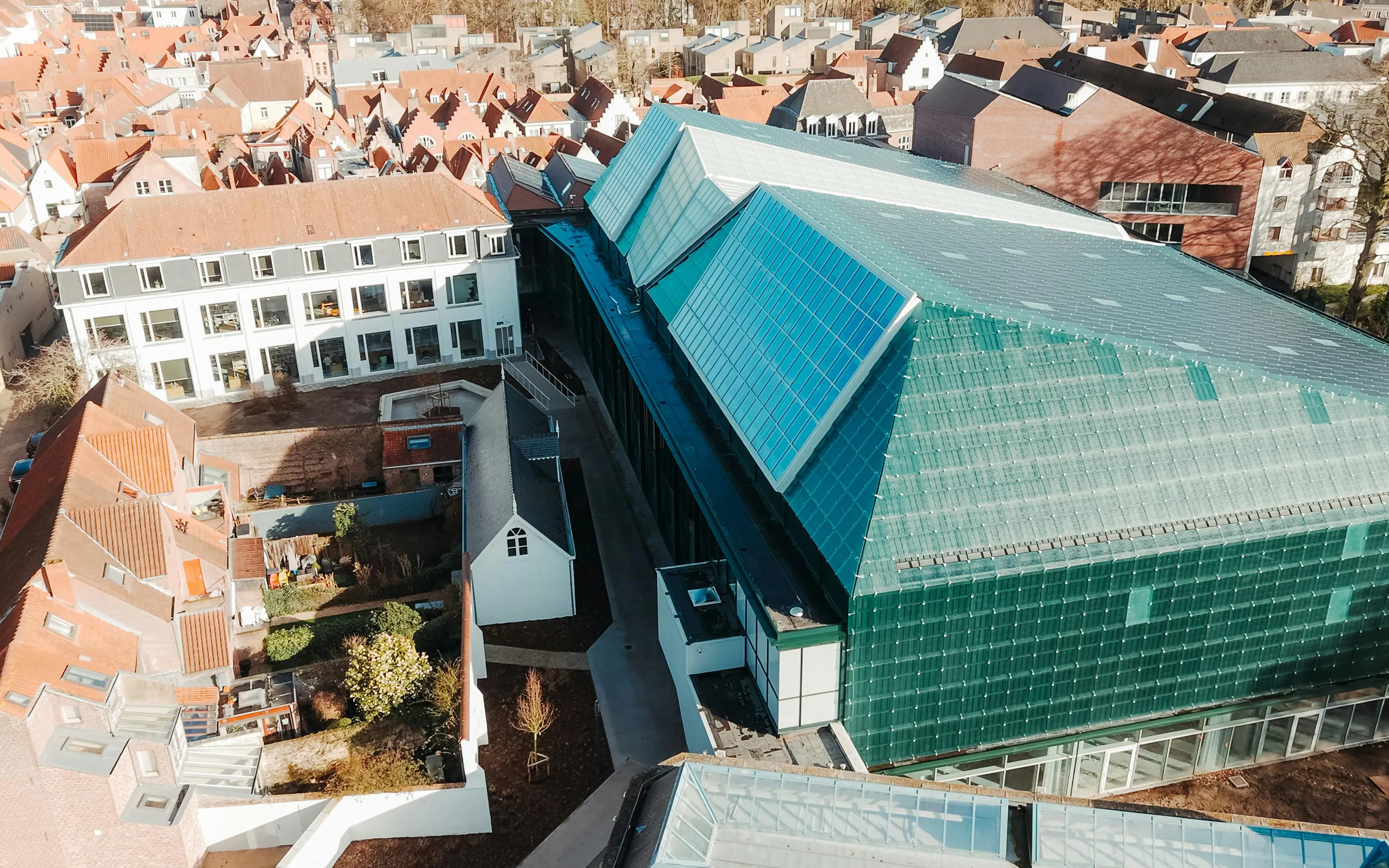 Aerial view of BRUSK building with modern glass roof in a historic cityscape.