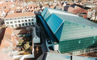Aerial view of BRUSK building with modern glass roof in a historic cityscape.