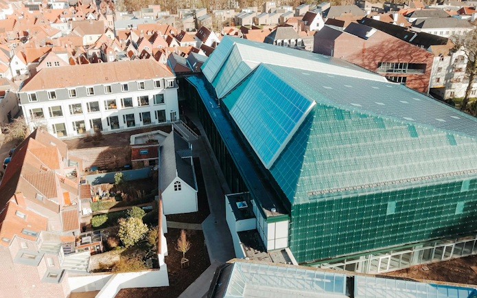 Aerial view of BRUSK building with modern glass roof in a historic cityscape.
