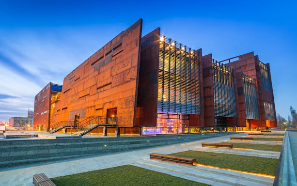 Exterior view of the European Solidarity Center in Gdańsk, Poland at dusk.