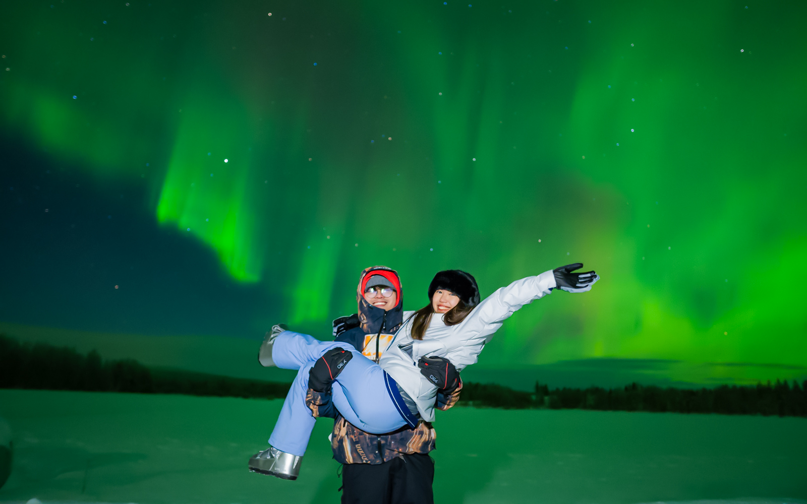 Couple enjoying Northern Lights in Levi, Finland.