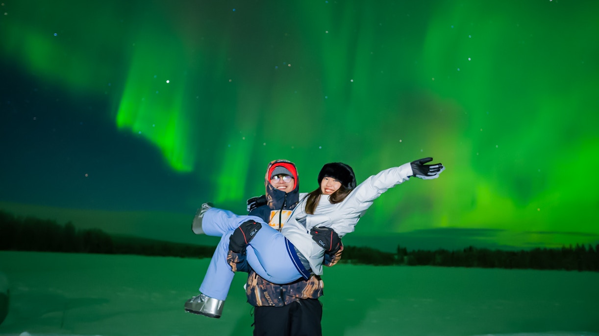 Couple enjoying Northern Lights in Levi, Finland.