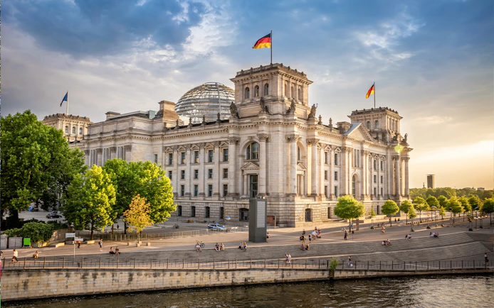 Reichstag building in Berlin's parliament district with people walking nearby.