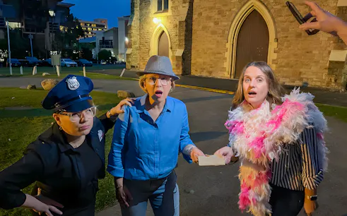 Participants on Fortitude Valley's True Crime Guided Tour acting out a scene near a historic building.