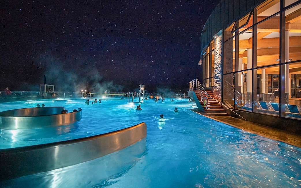 Visitors enjoying Chocholow Thermal Baths at night under a starry sky.