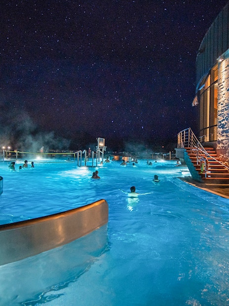 Visitors enjoying Chocholow Thermal Baths at night under a starry sky.