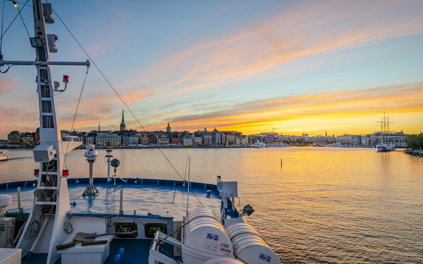 Ship deck view at sunset with Stockholm skyline in the background.