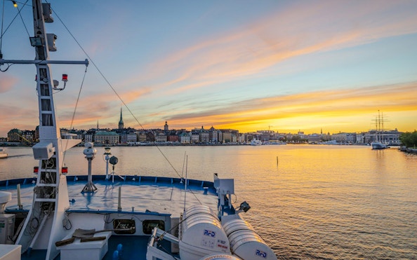 Ship deck view at sunset with Stockholm skyline in the background.