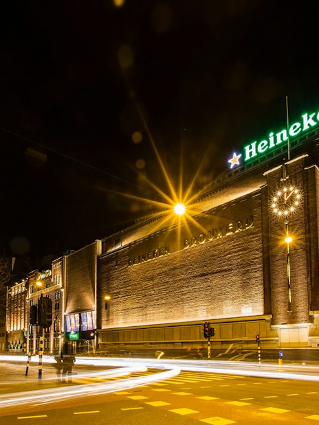Heineken Experience building illuminated at night in Amsterdam.