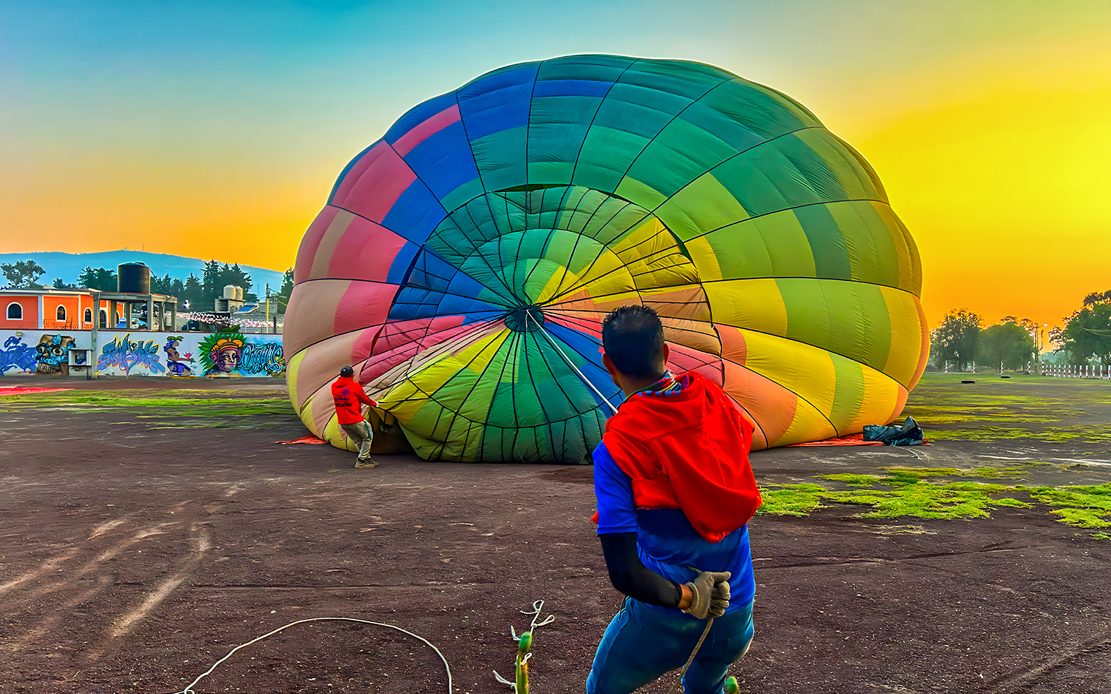 Preparing a colorful hot air balloon for flight at sunrise in Teotihuacan, Mexico.