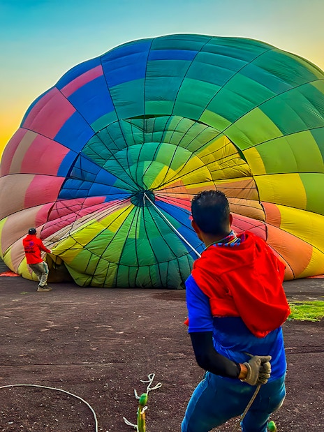 Preparing a colorful hot air balloon for flight at sunrise in Teotihuacan, Mexico.