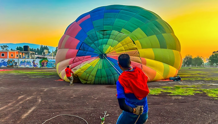 Hot air balloon inflating at Teotihuacan, Mexico, with ancient pyramids in the background.
