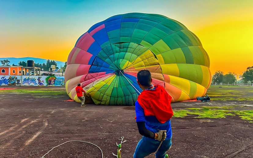 Preparing a colorful hot air balloon for flight at sunrise in Teotihuacan, Mexico.