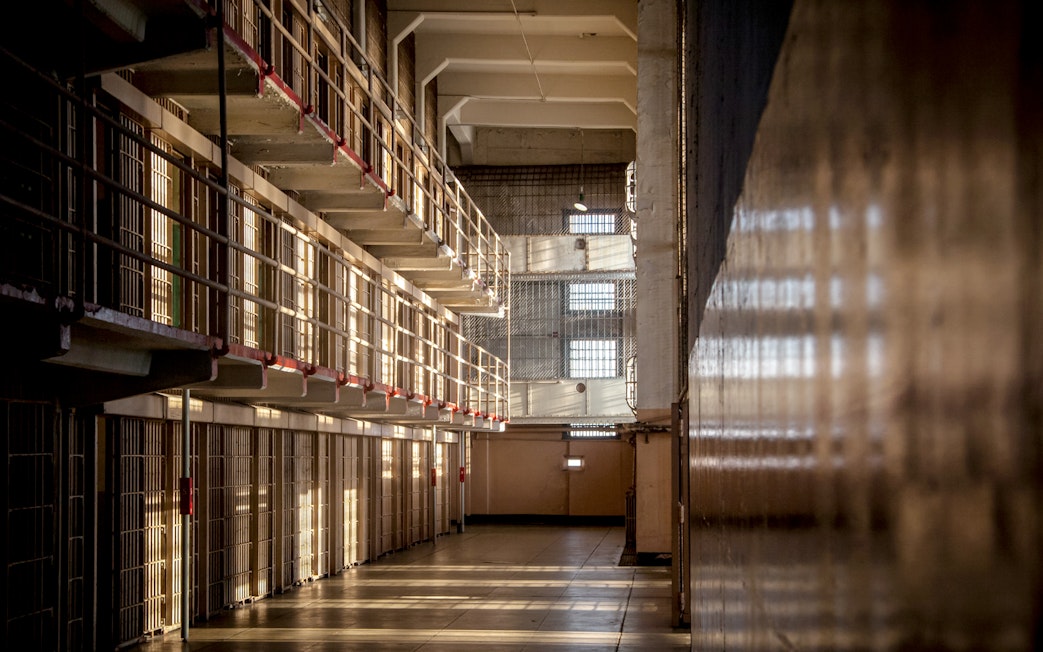 Alcatraz prison cell block interior with sunlight streaming through barred windows, San Francisco tour.