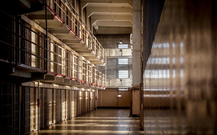 Alcatraz prison cell block interior with sunlight streaming through barred windows, San Francisco tour.