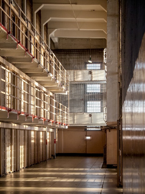Alcatraz prison cell block interior with sunlight streaming through barred windows, San Francisco tour.