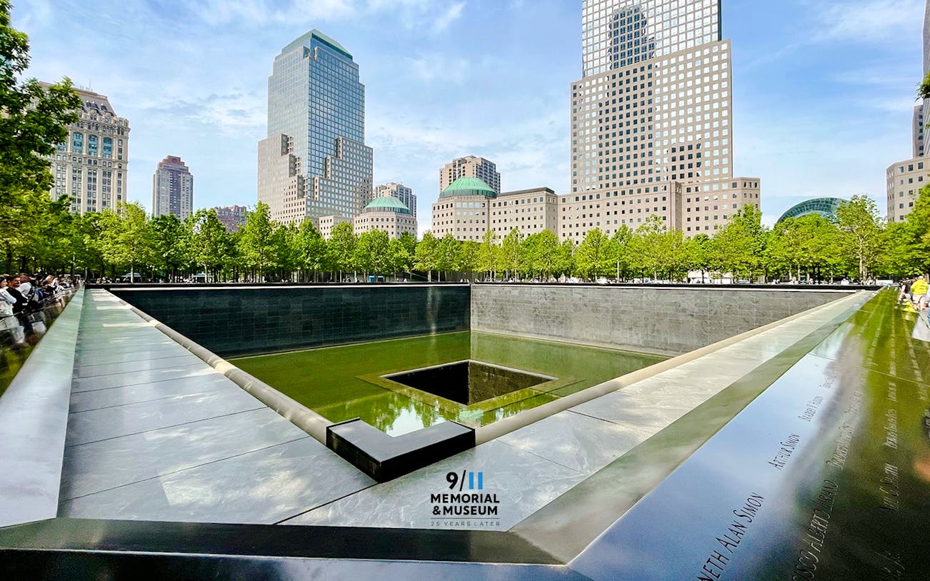 Reflecting pool at 9/11 Memorial in New York City with surrounding skyscrapers.