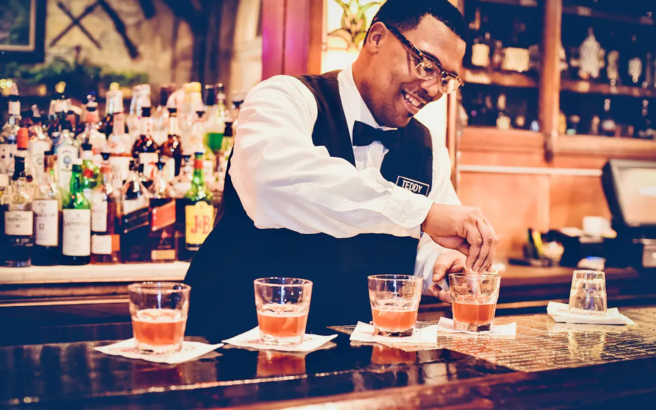 Bartender preparing cocktails at a bar in New Orleans during a craft cocktail walking tour.