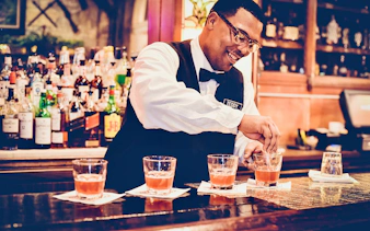 Bartender preparing cocktails at a bar in New Orleans during a craft cocktail walking tour.