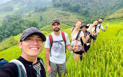 Group of tourists hiking through rice terraces in Sapa, Vietnam during a day tour.