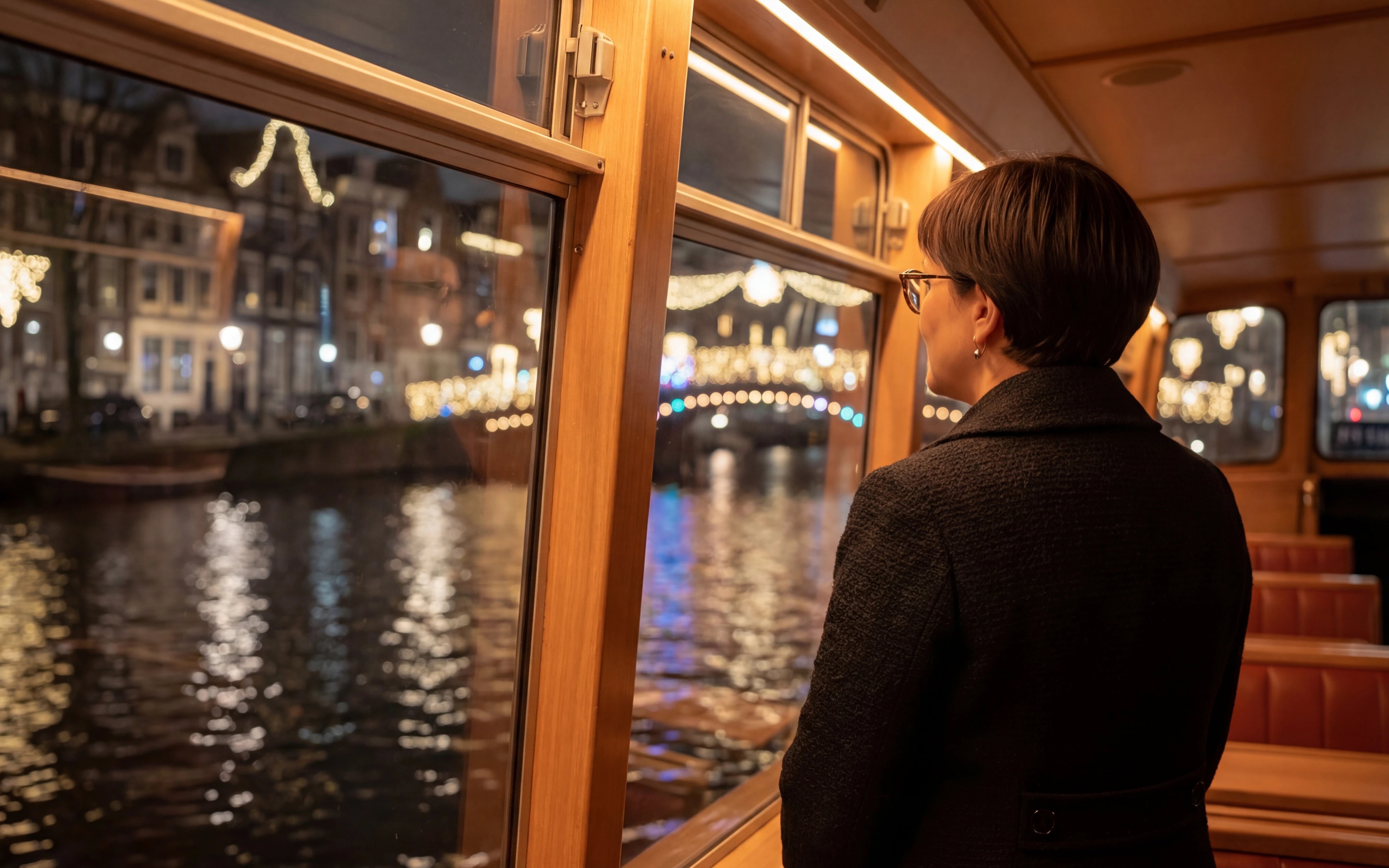 Passenger enjoying Amsterdam Light Festival from canal cruise boat.