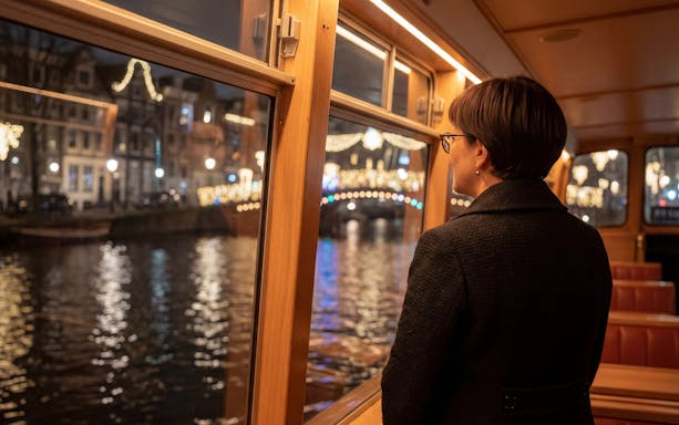 Passenger enjoying Amsterdam Light Festival from canal cruise boat.